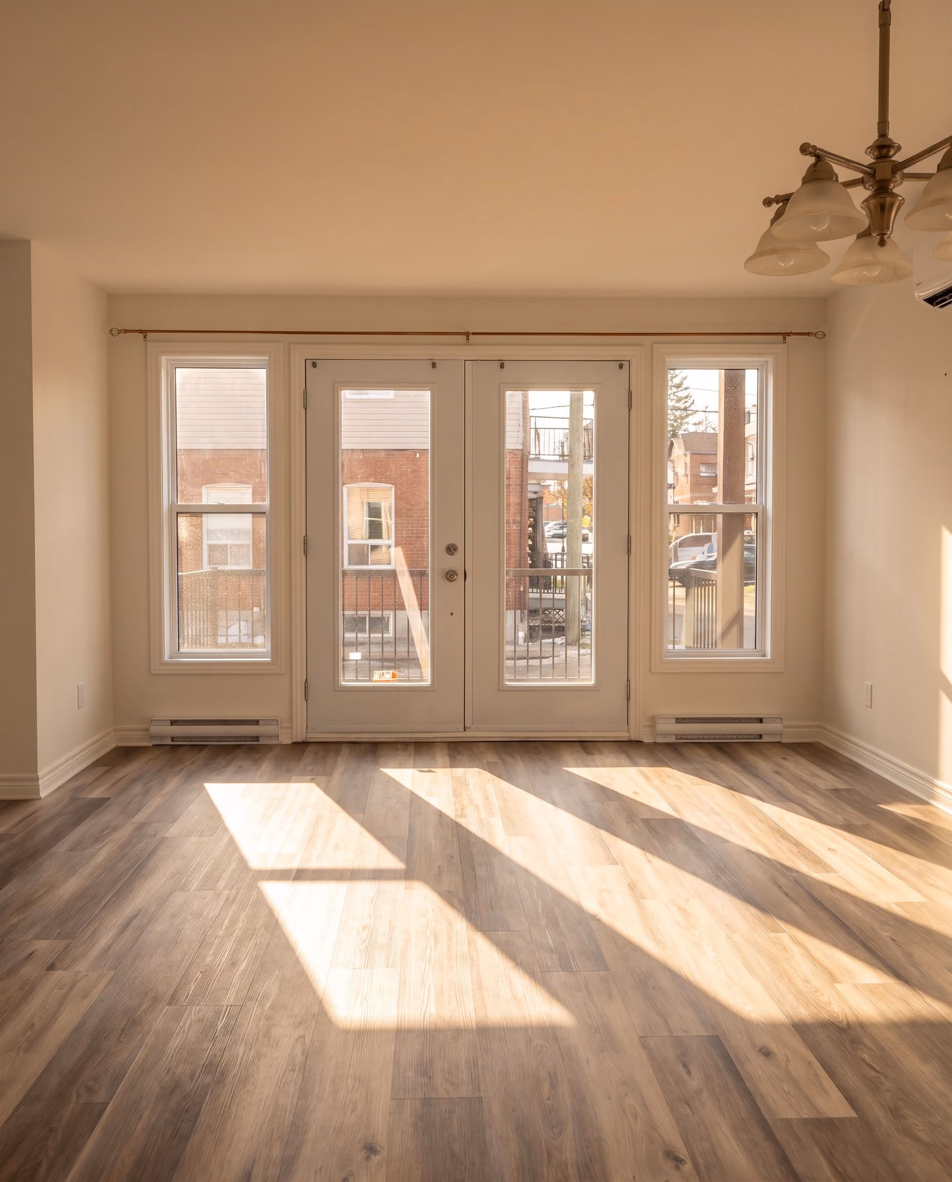 Glazed French doors seen from the living room, daylight drawing a rectangle on the wood floor.